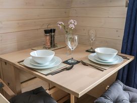 A dining table set with two place settings including bowls plates cutlery and wine glasses with a salt and pepper shaker and flowers in a glass vase at Holbein Matlock