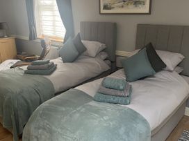 A bedroom with two beds and a chair at Rainbow's End in Swanton Morley
