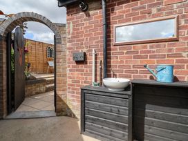 An outdoor garden area with a gate and a bowl on a shelf at The Corner House in Ufford near Woodbridge