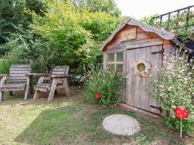 A children's playhouse and wooden chairs in a garden at The Corner House Ufford near Woodbridge