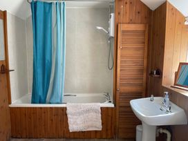 A bathroom featuring a bathtub with shower curtain and sink at Vinney Cottage in Owermoigne
