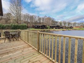 An outdoor area with a table and chairs by a lake at Lakeside Lodge Bowland Lakes Leisure Village near Garstang