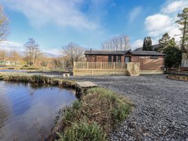 A lodge with a deck and pond at Lakeside Lodge Bowland Lakes Leisure Village near Garstang