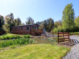A lodge with a deck beside a pond at Lakeside Lodge Bowland Lakes Leisure Village near Garstang