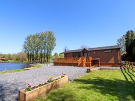A lodge with a deck by a lake at Lakeside Lodge Bowland Lakes Leisure Village near Garstang