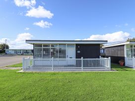 A single-story black and white house with a small front porch and green grass at 104 The Laurels in Chapel St Leonards