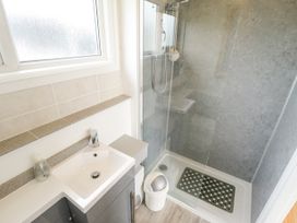 A bathroom with a sink and cabinet next to a glass-enclosed shower at 104 The Laurels in Chapel St Leonards