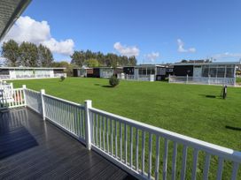 A view of multiple single-story residential units with white fences and green lawns at 104 The Laurels in Chapel St Leonards