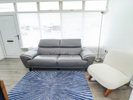 A living room with a grey sofa a white chair a blue striped rug and a standing lamp at 104 The Laurels in Chapel St Leonards