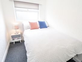 A bedroom with a bed with two cushions and a bedside table with a lamp at 104 The Laurels in Chapel St Leonards