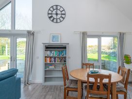 A dining room with a table and books on a shelf at Moranedd Bach in Holyhead