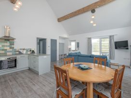 An open plan kitchen and living area with a dining table at Moranedd Bach in Holyhead