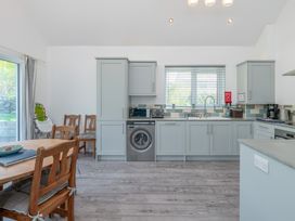 A kitchen with cabinets and dining table at Moranedd Bach in Holyhead
