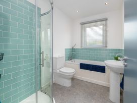 A bathroom with a shower, toilet, bathtub, and sink at Moranedd Bach in Holyhead