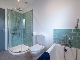 A bathroom with shower, toilet, and bathtub at Moranedd Bach in Holyhead