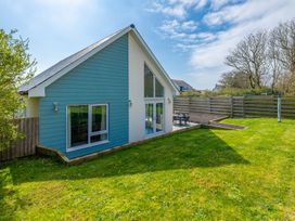 A house with grass and a deck in the garden at Moranedd Bach in Holyhead