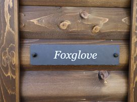 A close up of a wooden wall with a dark plaque that reads Foxglove at Higher Wambrook near Chard