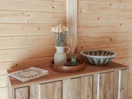 A wooden cabinet with a guest book a vase with dried flowers a reed diffuser and a woven basket on top at Foxglove in Higher Wambrook near Chard