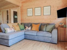 A living room with a grey sectional sofa and multiple cushions under three framed pictures at Foxglove in Higher Wambrook near Chard