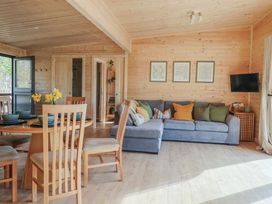 A living room with a dining table and chairs a blue sofa and a wall-mounted tv at Foxglove in Higher Wambrook near Chard