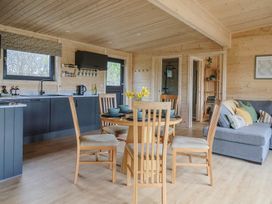 A wooden dining table with chairs in a kitchen area with blue cabinets and a gray sofa with pillows at Foxglove in Higher Wambrook near Chard