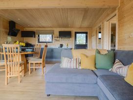 A kitchen and dining area with wooden chairs and a gray sofa with cushions at Foxglove in Higher Wambrook near Chard