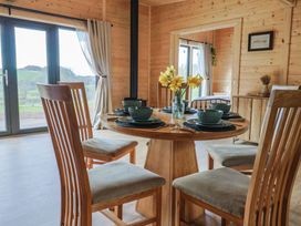 A dining area with wooden chairs and a round table set with dishes and a vase of yellow flowers at Foxglove in Higher Wambrook near Chard