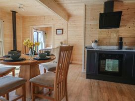 A wooden dining room with a round table set for four near a black kitchen oven and stove at Foxglove in Higher Wambrook near Chard