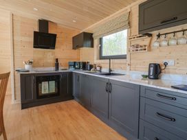A kitchen with dark cabinets wooden walls window and various appliances at Foxglove in Higher Wambrook near Chard