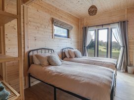 A bedroom with two single beds wooden walls and a large window with curtains at Foxglove in Higher Wambrook near Chard