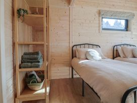 A bedroom with two single beds a shelf with towels and a small window at Foxglove in Higher Wambrook near Chard