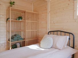 A bedroom with a single bed and a wooden shelving unit holding towels and plants at Foxglove in Higher Wambrook near Chard