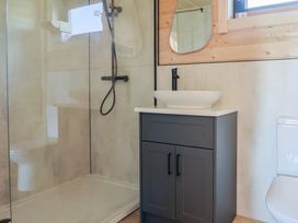 A bathroom with a shower area a dark gray cabinet with a white basin and a toilet at Foxglove Higher Wambrook near Chard