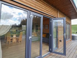 A wooden house exterior with glass door open showing dining table and chairs inside at Foxglove in Higher Wambrook near Chard