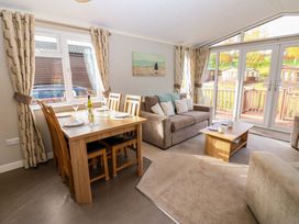 A living room with dining table and chairs a sofa coffee table and large windows at Dragonfly in Tunstall near Hipswell