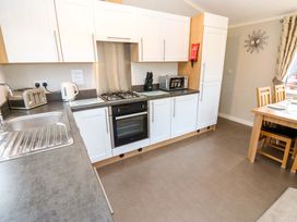 A kitchen with white cabinets a stainless steel sink gas stove oven microwave dining table and chairs at Dragonfly in Tunstall near Hipswell