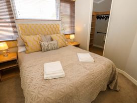 A bedroom with a bed with folded towels on it two bedside tables with lamps and a walk-in closet at Dragonfly in Tunstall near Hipswell