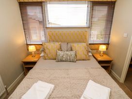 A bedroom with a bed with pillows and folded towels on a blanket and bedside tables with lamps at Dragonfly in Tunstall near Hipswell