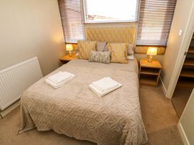 A bedroom with a bed two bedside tables lamps and folded towels at Dragonfly in Tunstall near Hipswell