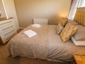 A bedroom with a bed made with beige bedding and pillows a chest of drawers and a window with blinds at Dragonfly Tunstall near Hipswell
