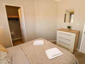 A bedroom with a bed with folded towels a chest of drawers with a plant and an open door to a closet at Dragonfly in Tunstall near Hipswell