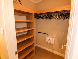 A walk-in closet with wooden shelves and hanging rods with clothes hangers at Dragonfly in Tunstall near Hipswell