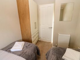 A bedroom with two beds a wardrobe a door a radiator and a mirror at Dragonfly in Tunstall near Hipswell