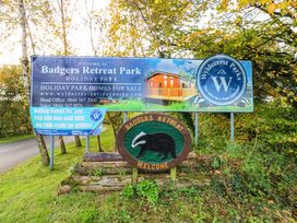 A sign for Badgers Retreat Park holiday park with information about holiday homes for sale surrounded by trees and grass at Dragonfly in Tunstall near Hipswell