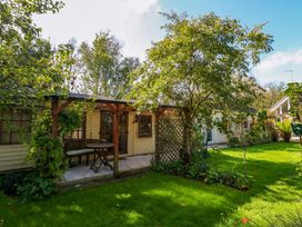 A garden with a shed, table, and trees at The Cabin at Little Timbers Ringwood