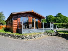 A lodge with a deck and chairs at Dovedale Lodge Troutbeck Bridge