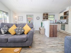 A living room with a sofa and dining area at Dovedale Lodge in Troutbeck Bridge