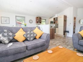 A living room with a sofa and kitchen area at Dovedale Lodge Troutbeck Bridge
