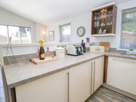 A kitchen with a toaster, storage containers, and a clock at Dovedale Lodge, Troutbeck Bridge