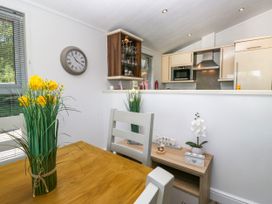 A kitchen with a clock and flowers on the table at Dovedale Lodge in Troutbeck Bridge